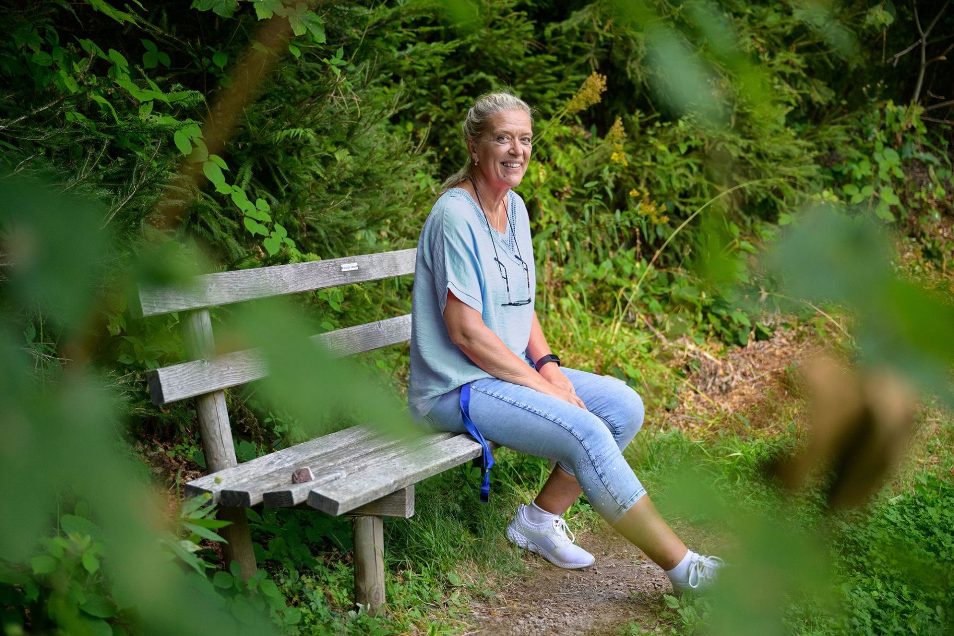 Ute Gehring sitzt auf einer Bank im Wald.
