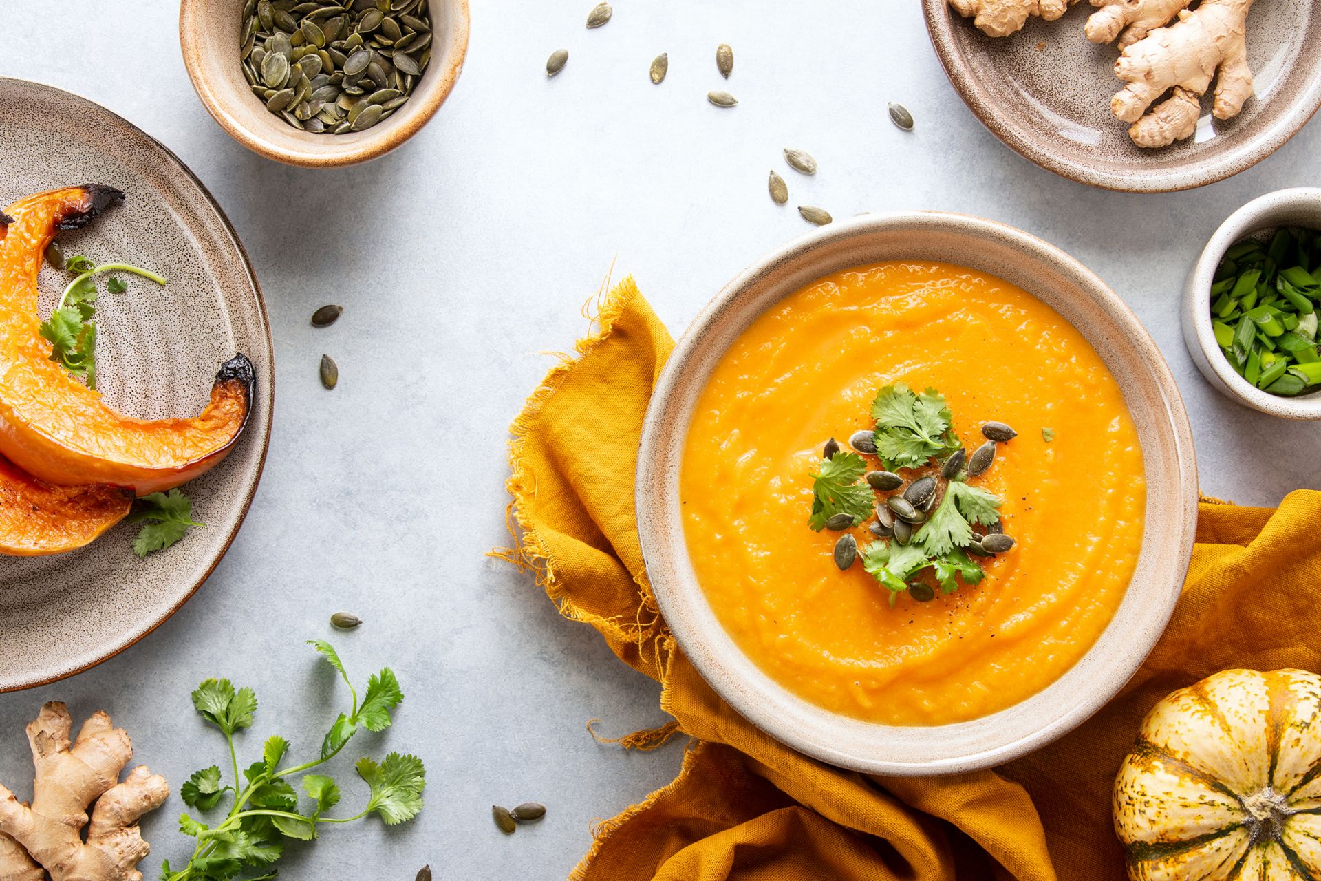 Kürbiscremesuppe in einer Schale, mit Kürbiskernen und Koriander dekoriert.