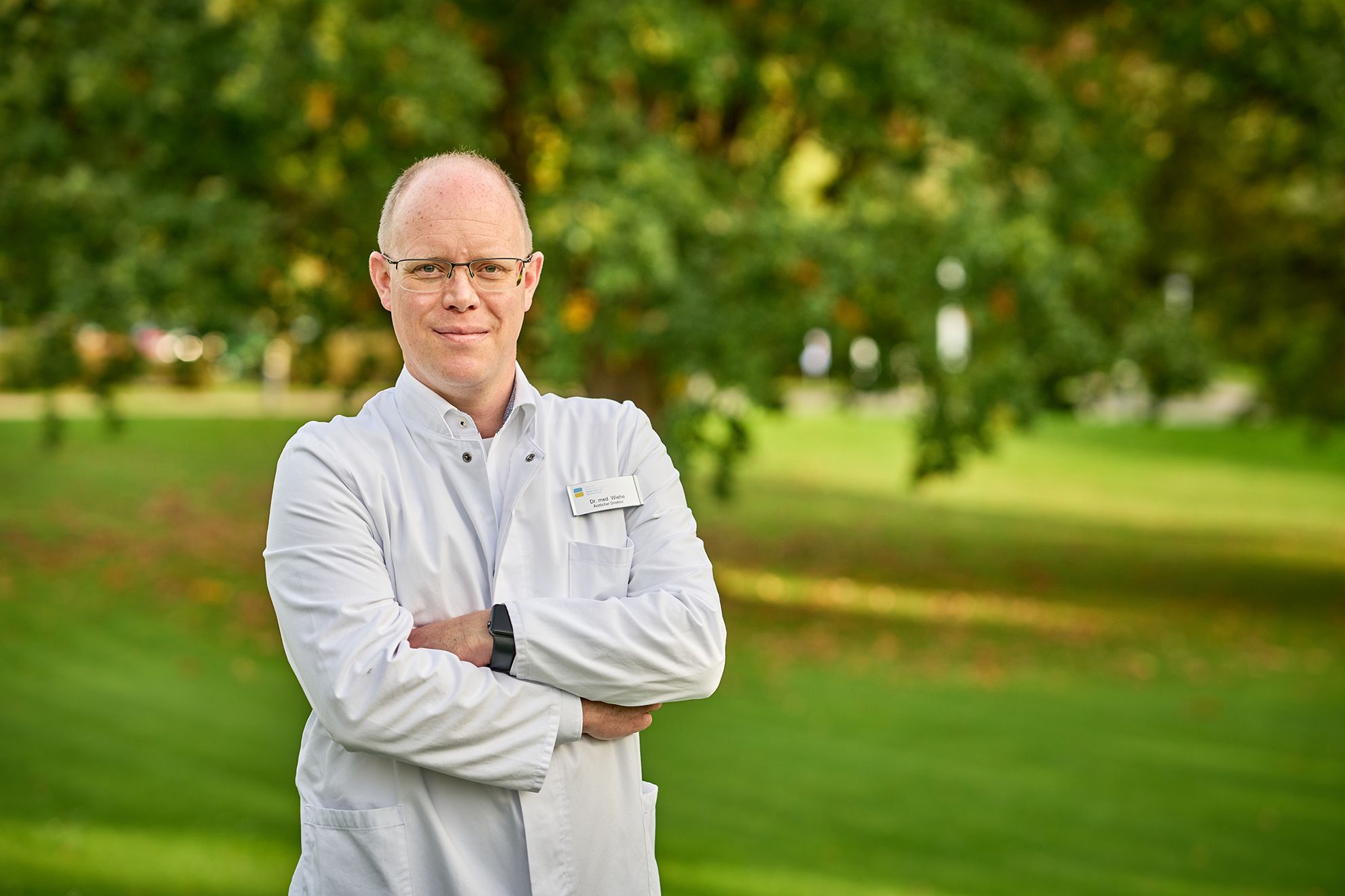 Porträt von Dr. Rainer Wiehe auf einer grünen Wiese mit Bäumen.